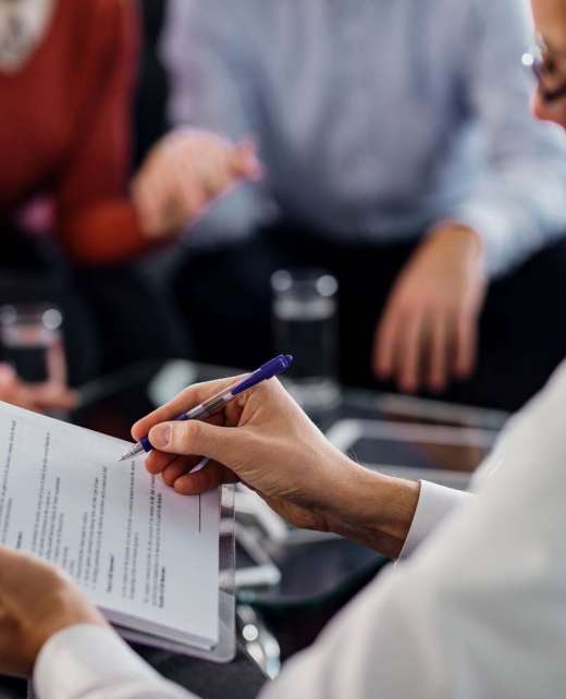 Close-up of insurance agent analyzing an agreement while having consultations with clients in the office.