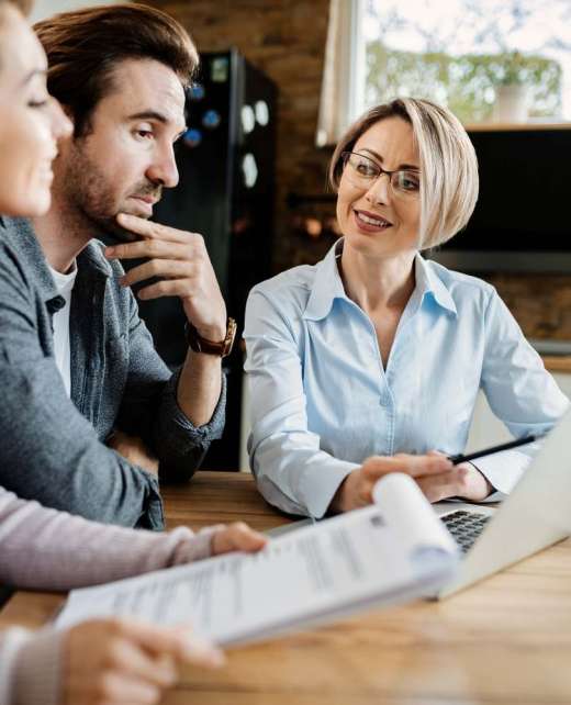 Smiling insurance agent and young couple using computer on a meeting at home.