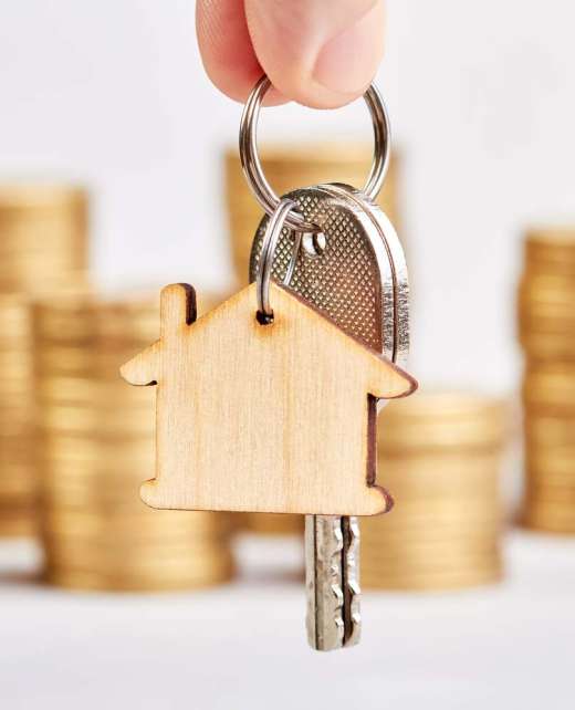 A man holds the keys to a new apartment against the background of stacks of coins