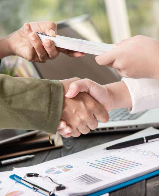 Business people shaking hands, finishing up meeting. businessman giving money to his partner while making contract - bribery and corruption concepts.